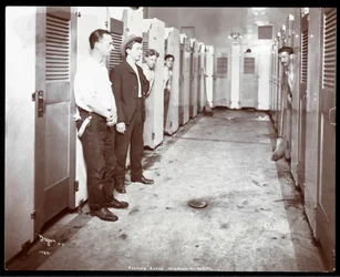 Vista interior de jóvenes asomándose desde cabinas de baño en los Baños del Pueblo, Milbank Memorial, Nueva York, 1904